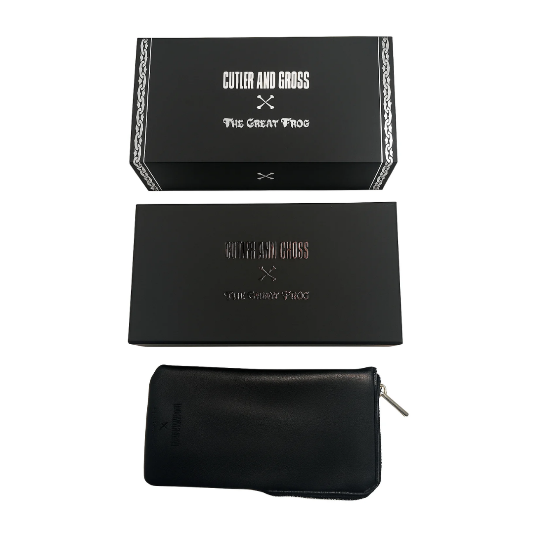 A black leather zippered pouch shown with its matching black presentation box and inner box on a plain white background. The packaging features the Cutler and Gross x The Great Frog.